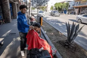 Jóvenes barberos solidarios Tijuana realizando un corte de cabello gratuito en una calle de la ciudad